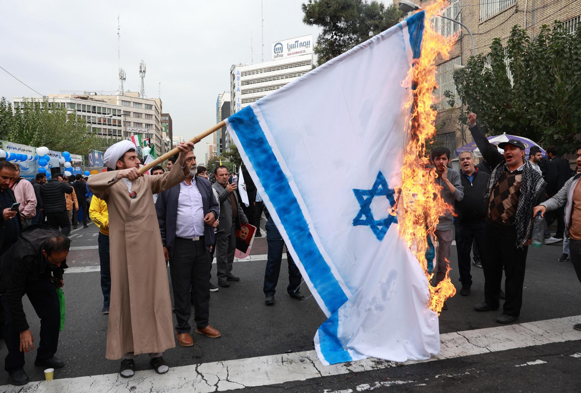 Un clérigo iraní quema una bandera israelí durante una concentración contra Estados Unidos con motivo del 45 aniversario de la toma de la embajada estadounidense, frente al antiguo edificio de la legación diplomática en Teherán, el 3 de noviembre de 2024. EFE/EPA/ABEDIN TAHERKENAREH
