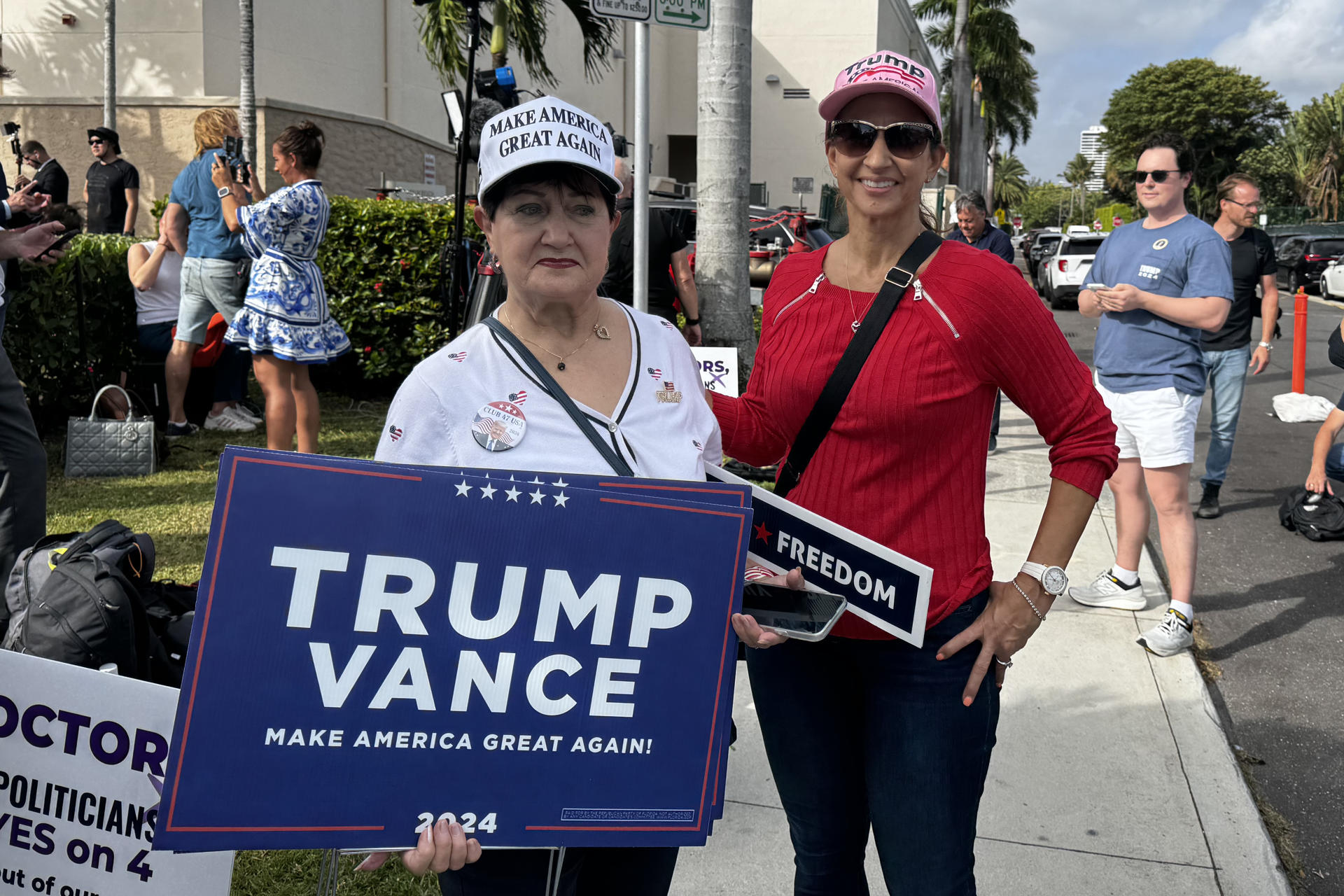 Dos simpatizantes del expresidente y candidato republicano Donald Trump muestran carteles de apoyo al candidato, este martes en Palm Beach, Florida (Estados Unidos). Decenas de simpatizantes de Donald Trump se reunieron en el centro de votación del Morton and Barbara Mandel Recreation Center, de Palm Beach (Florida, EE.UU.), para apoyarlo y acompañarlo a votar en el lugar. EFE/ Alicia Civita
