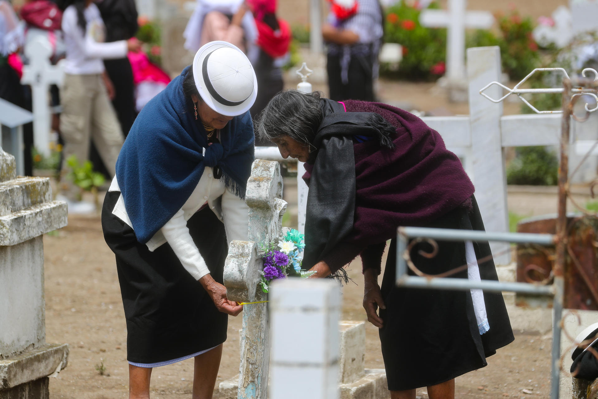 Dos mujeres decoran una tumba durante la conmemoración del Día de Muertos este sábado, en la comunidad de Punin (Ecuador). EFE/ José Jácome