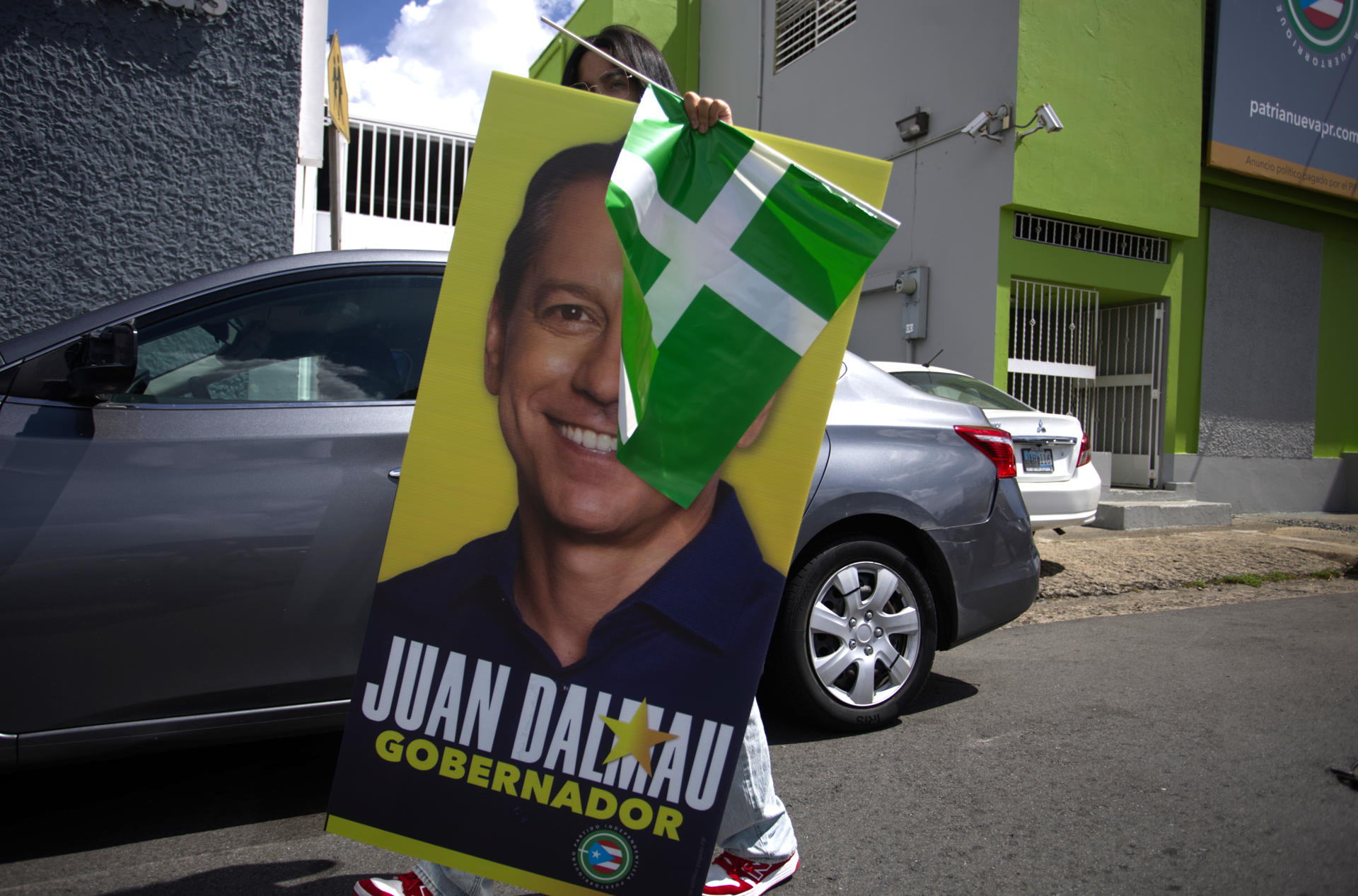 Fotografía del 25 de octubre de 2024 de una persona con un cartel electoral del candidato a la Gobernación de Puerto Rico por el Partido Independentista Puertorriqueño en alianza con el Movimiento Victoria Ciudadana, Juan Dalmau, en una calle de San Juan (Puerto Rico). EFE/ Thais Llorca