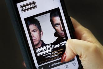 Una persona observa el póster promocional de la gira mundial de la banda británica Oasis. EFE/ANDY RAIN