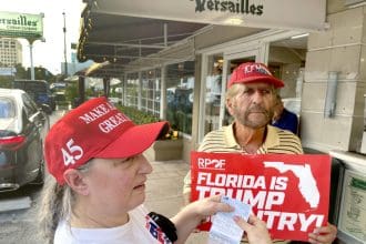 Ania Fresquet (i), una votante inscrita en la lista demócrata pero que vota por Donald Trump, muestra su tarjeta de votación junto a Miguel Saavedra, de la 'Vigilia Mambisa', el lunes 4 de noviembre de 2024 en frente del icónico restaurante Versailles de la Pequeña Habana en Miami, Florida (EE.UU.). EFE/Ana Milena Varón