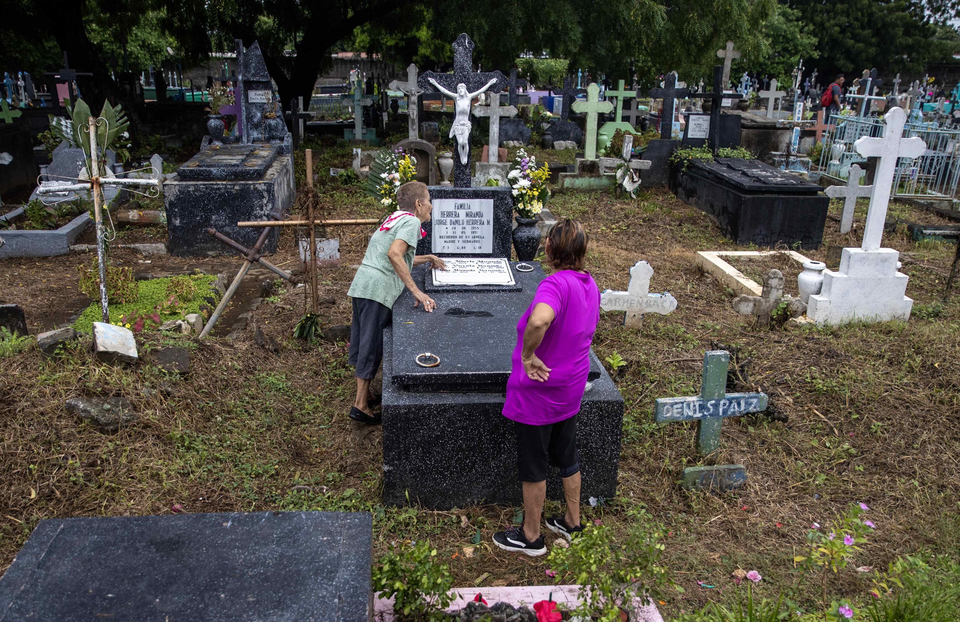Dos mujeres visitan la tumba de un familiar, en el marco de Día de Muertos, este sábado en un cementerio de Managua (Nicaragua). EFE/Stringer
