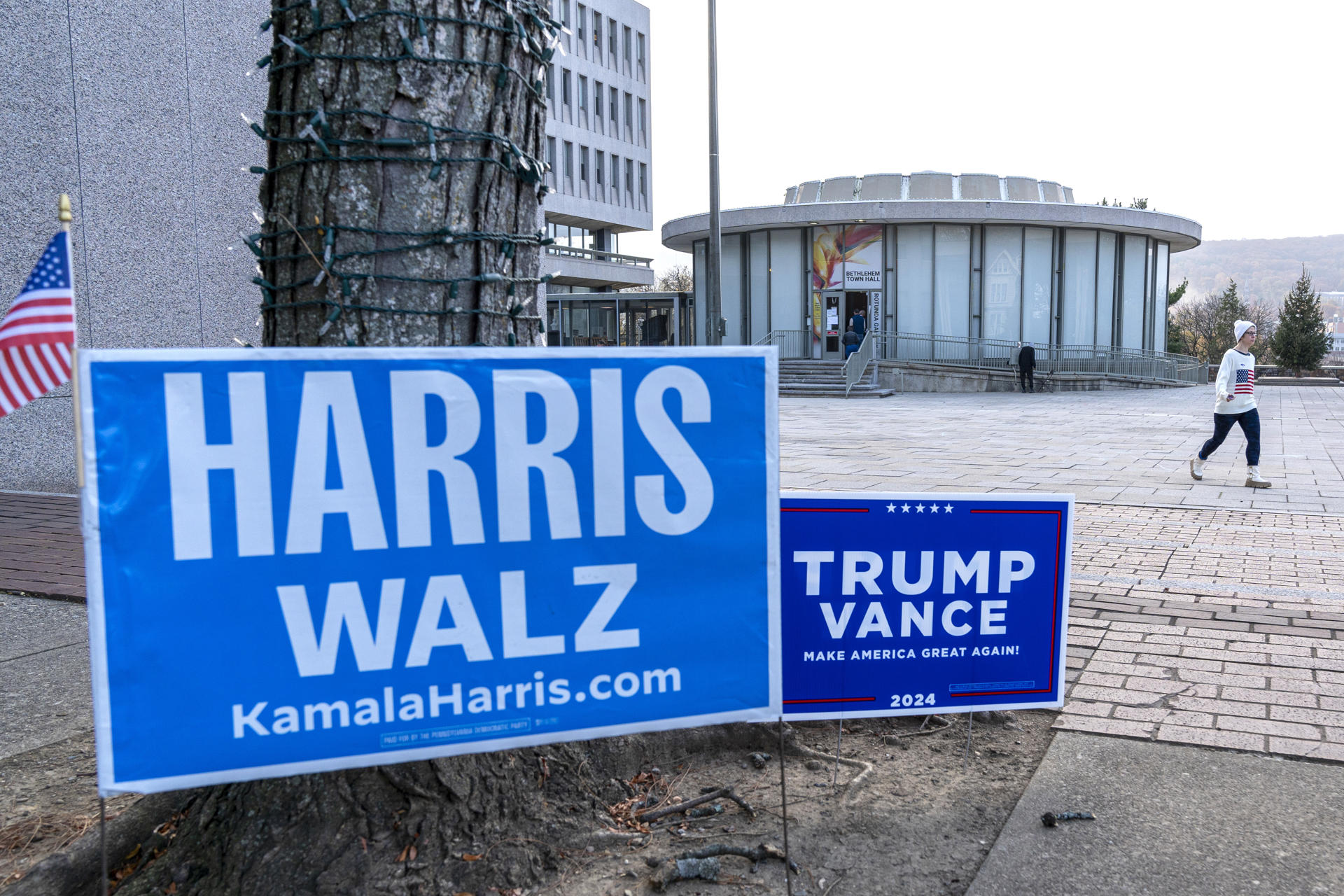 Una persona camina junto a carteles de los candidatos presidenciales, los demócratas Harris y Walz y los republicanos Trump y Vance, en la entrada de un centro de votación instalado en el gimnasio de la Escuela Secundaria Nitschmann, este martes, en Bethlehem, Pensilvania (Estados Unidos). EFE/Ángel Colmenares
