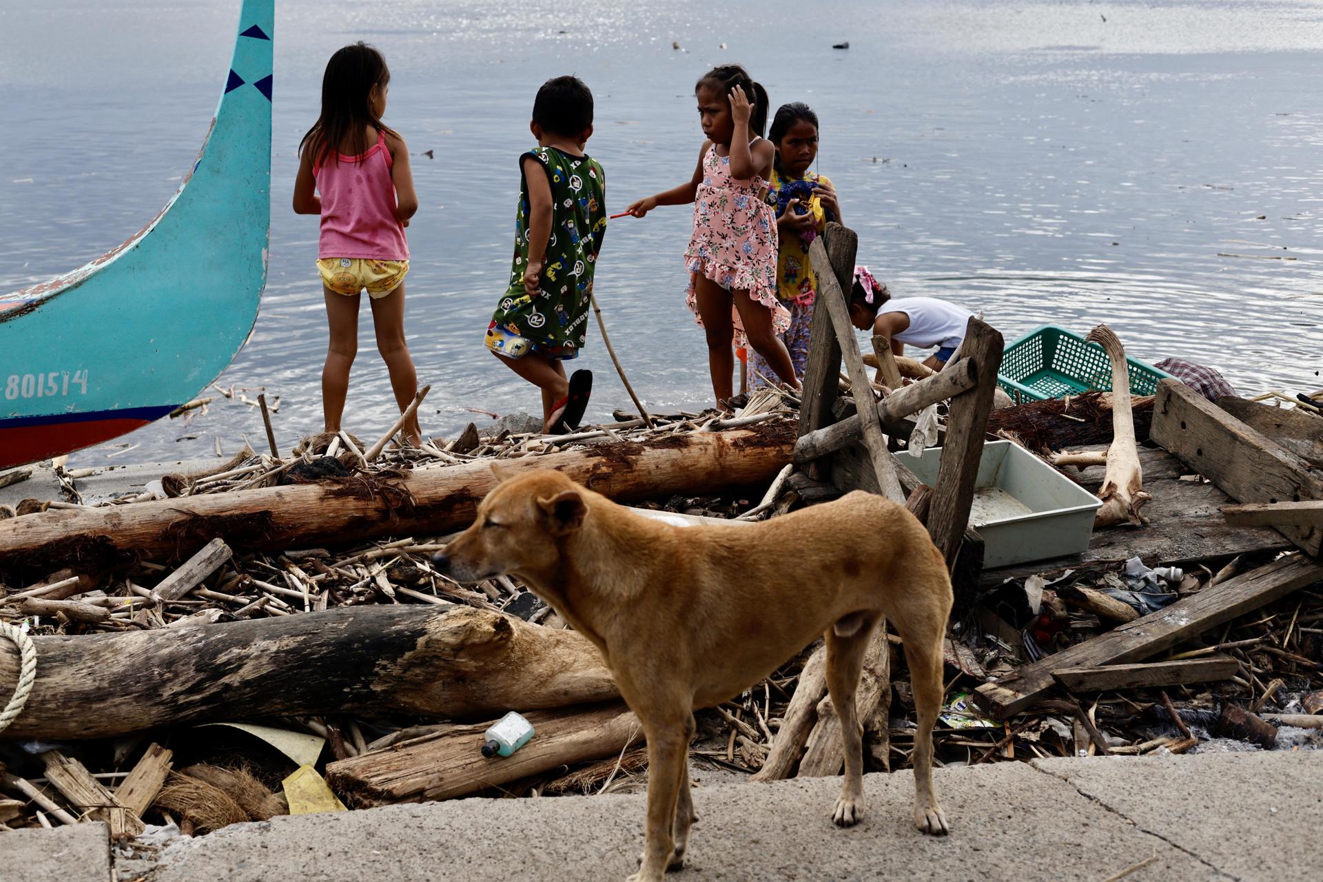 Varios niños juegan el domingo cerca de maderas y restos dejados por las recientes tormenta Trami y el tifón Kong-rey en la provincia de Batangas, en la isla filipina de Luzón. EFE/EPA/FRANCIS R. MALASIG
