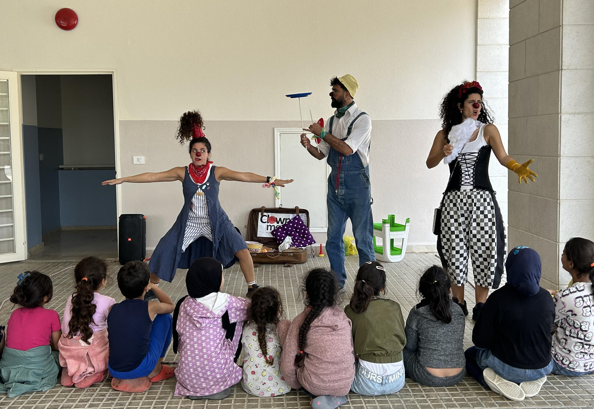 Payasos de la asociación Clown me In actúan ante una veintena de niños en un centro social de la localidad libanesa de Baabdat como parte de su programa itinerante de espectáculos para atender la salud mental de los menores. EFE/Rosa Soto
