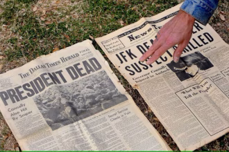Imagen de archivo de un hombre que muestra un periódico de 1963 que informa sobre el asesinato de Kennedy en el monumento en memoria de John F. Kennedy en Dealey Plaza, el lugar donde fue asesinado, en Dallas, Texas, EEUU. EFE/Larry W. Smith