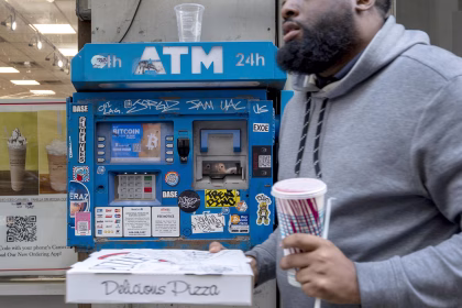 Una persona pasa frente a un cajero automático sosteniendo una comp´ra realizada en un almacén de comida en la ciudad de Nueva York (EE.UU.). EFE/ Ángel Colmenares