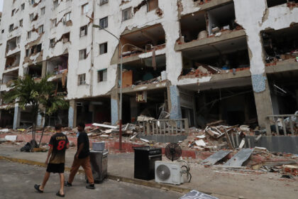 Personas caminan este sábado frente a edificios afectados por los terremotos ocurridos en la zona de Caraballeda, en La Guaira (Venezuela). EFE/ Raúl Martínez